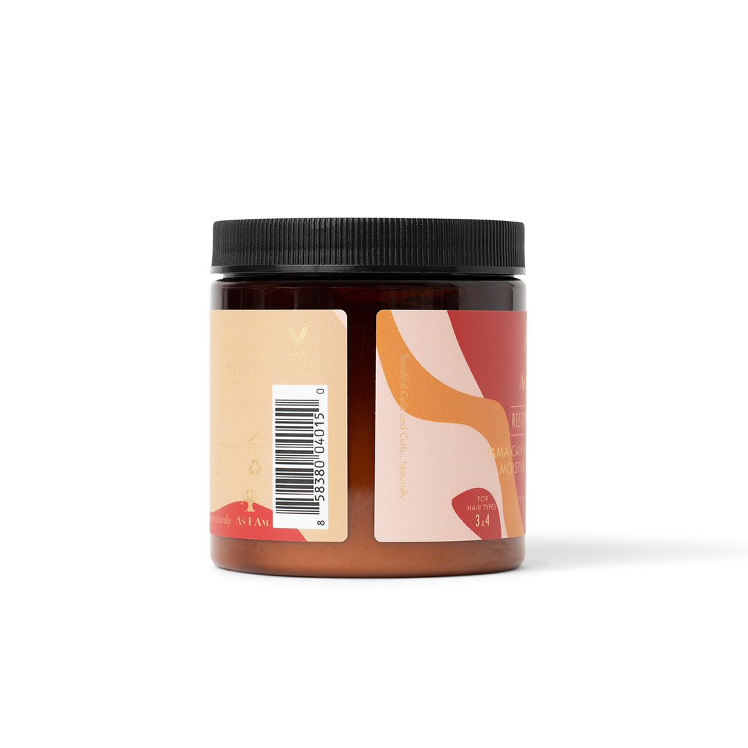 Siden af en mørk krukke As I Am Jamaican Black Castor Oil Moisturizing Masque (227 g) med en lyserød og beige etiket, der viser en stregkode og en del af produktinformationen.
