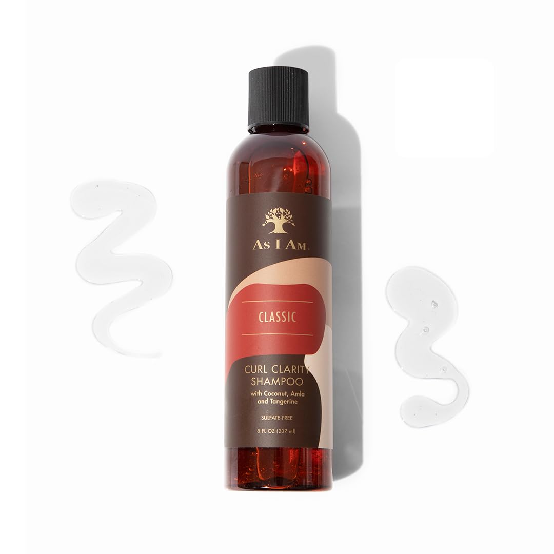 En brun shampoo-flaske med en hvid etiket står på en hvid baggrund. Flasken indeholder As I Am Curl Clarity Shampoo og har et billede af et træ på etiketten. Der er en klat shampoo i forgrunden.