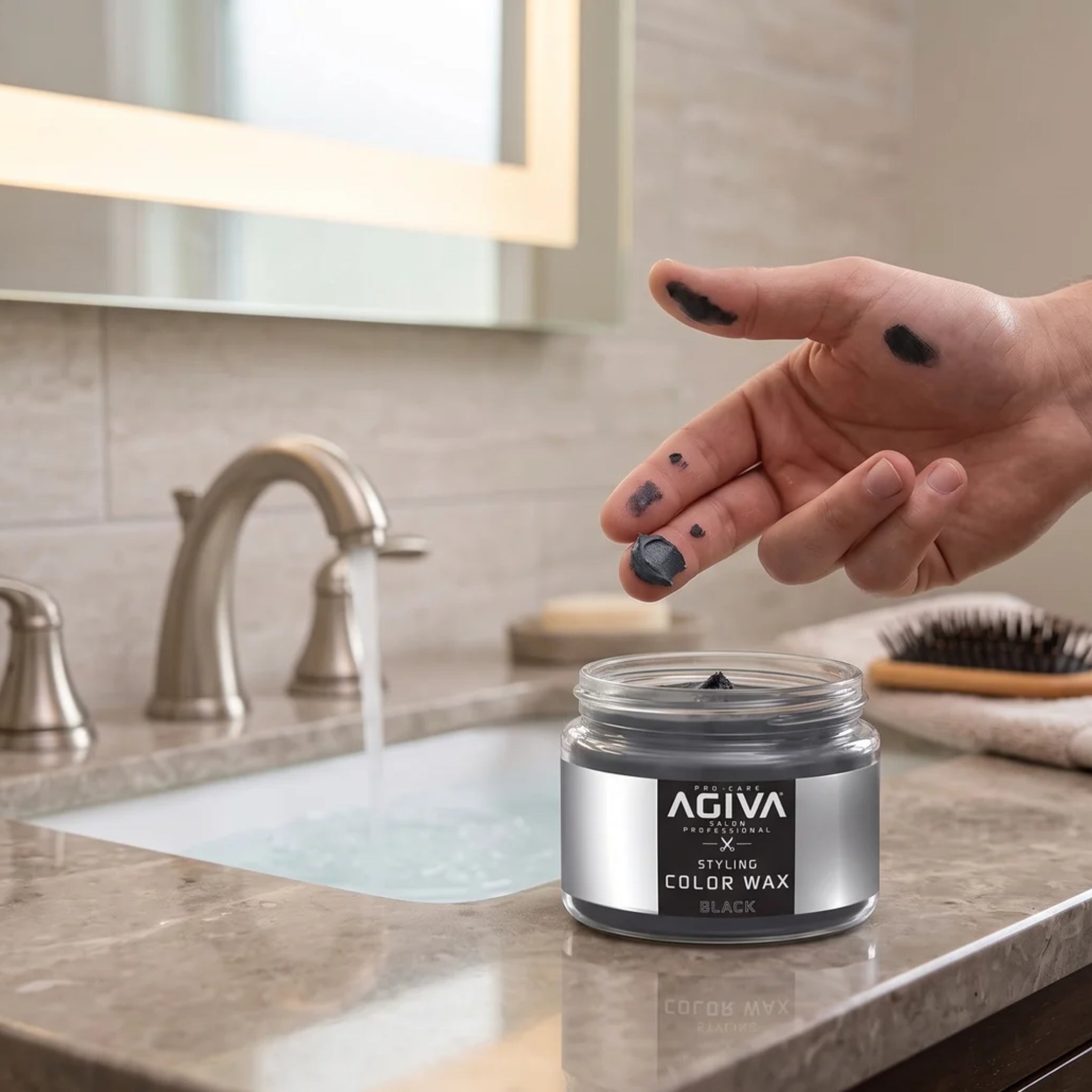 AGIVA Styling Color Wax Black i åben glasdåse på badeværelsesbord, hånd med sortfarvede fingre fra voksen.