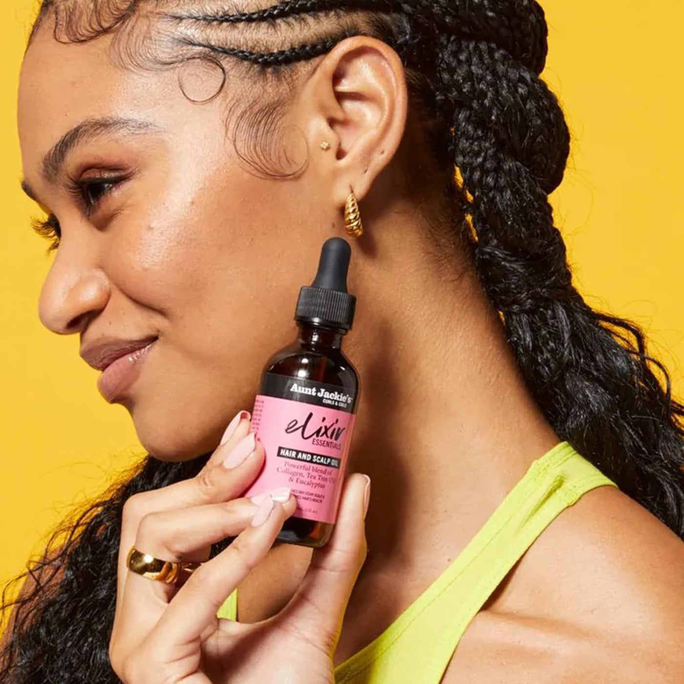 Kvinder der holder en flaske Aunt Jackie's Elixir Hair and Scalp Oil.