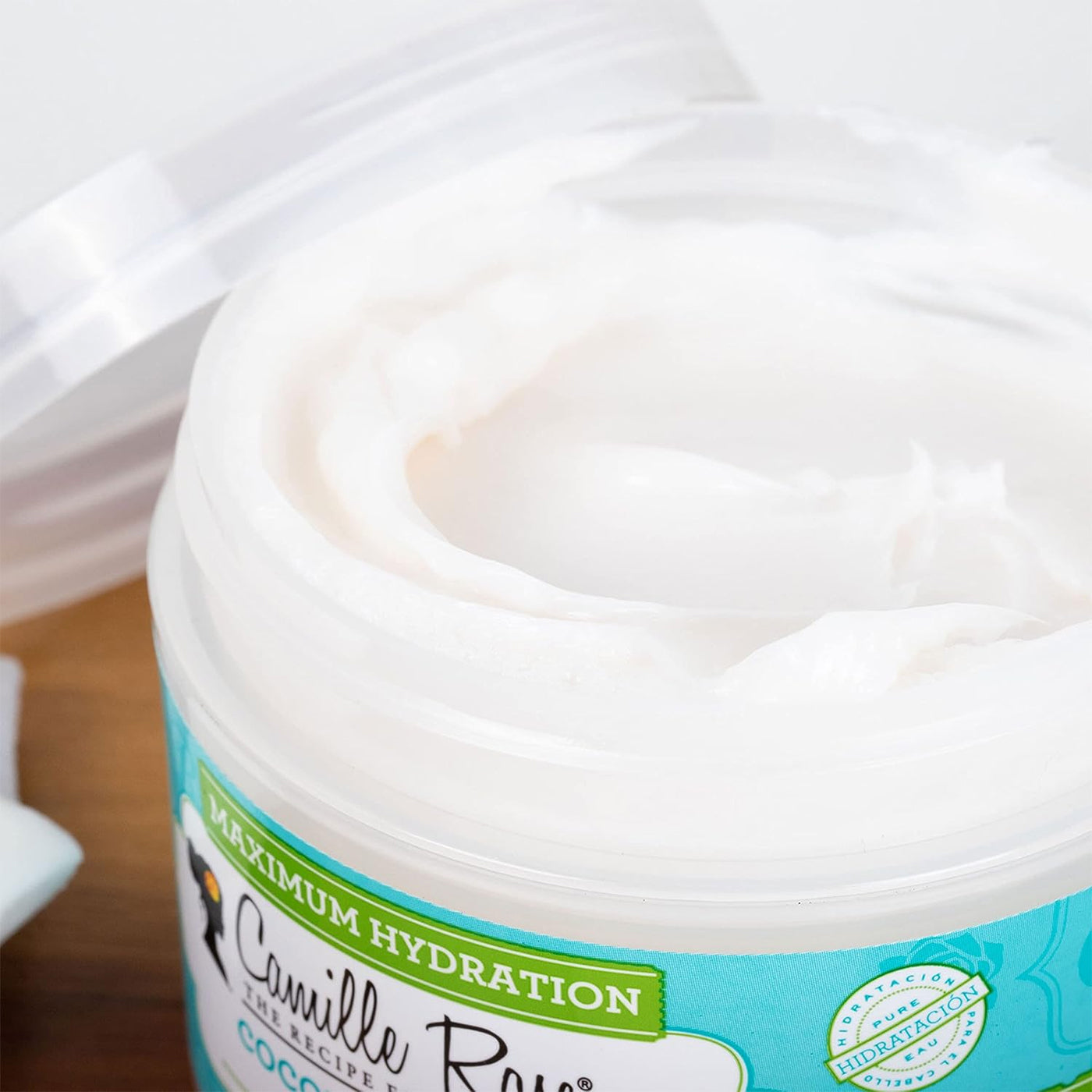 Nærbillede af den hvide, cremede konsistens af Camille Rose Coconut Water Penetrating Hair Treatment i en åben beholder.