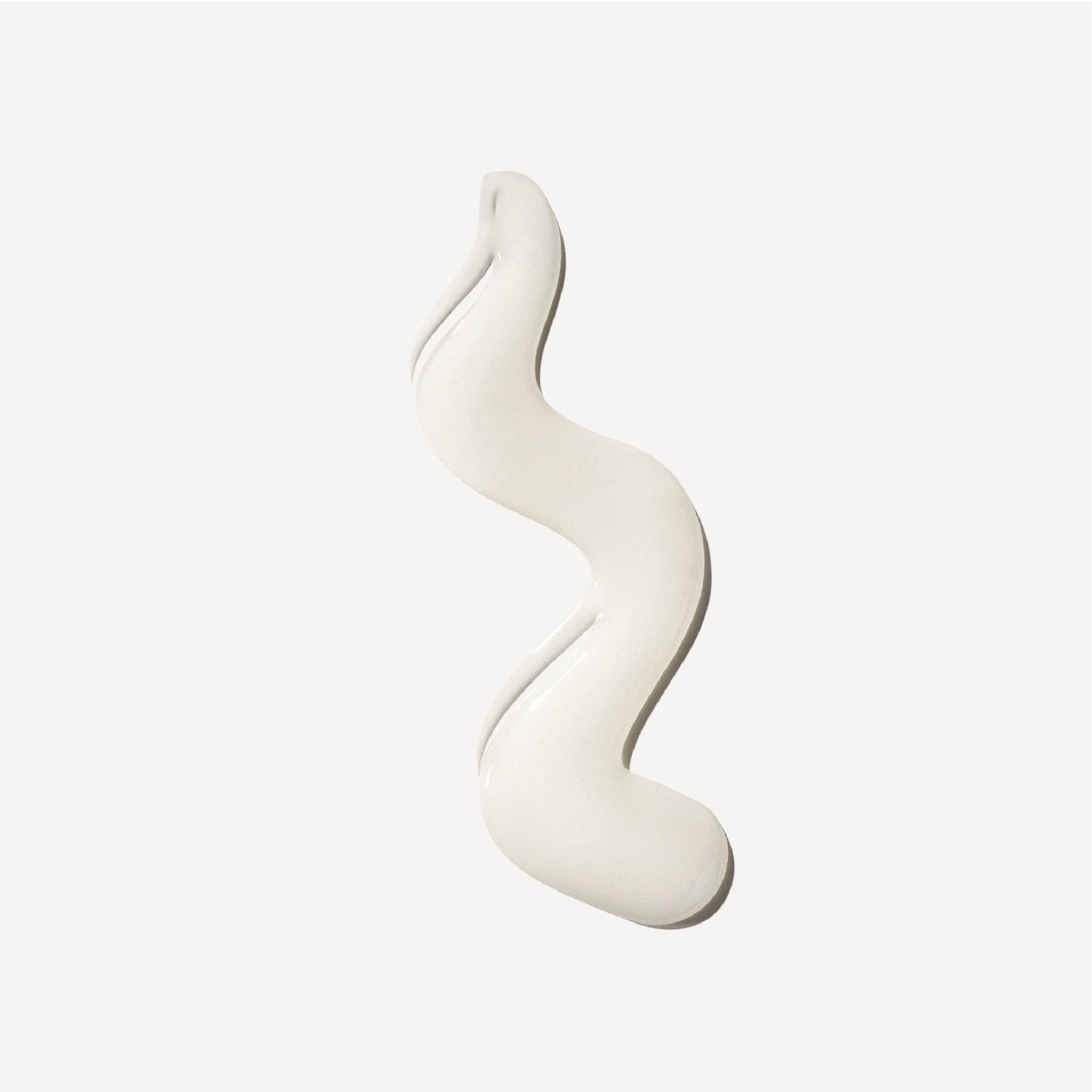 Snoet swirl af cremet hvid ansigtscreme på lys baggrund, glat og blank tekstur.