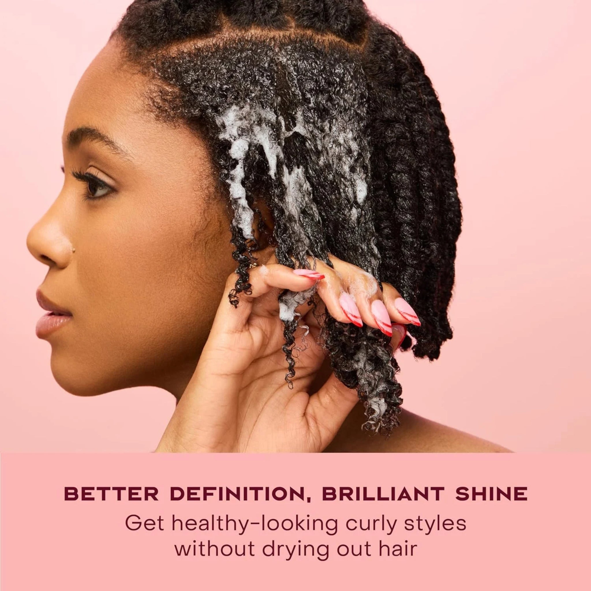 Kvinde masserer skummende shampoo ind i krøllet afro-hår for bedre definition og skinnende, sunde krøller.