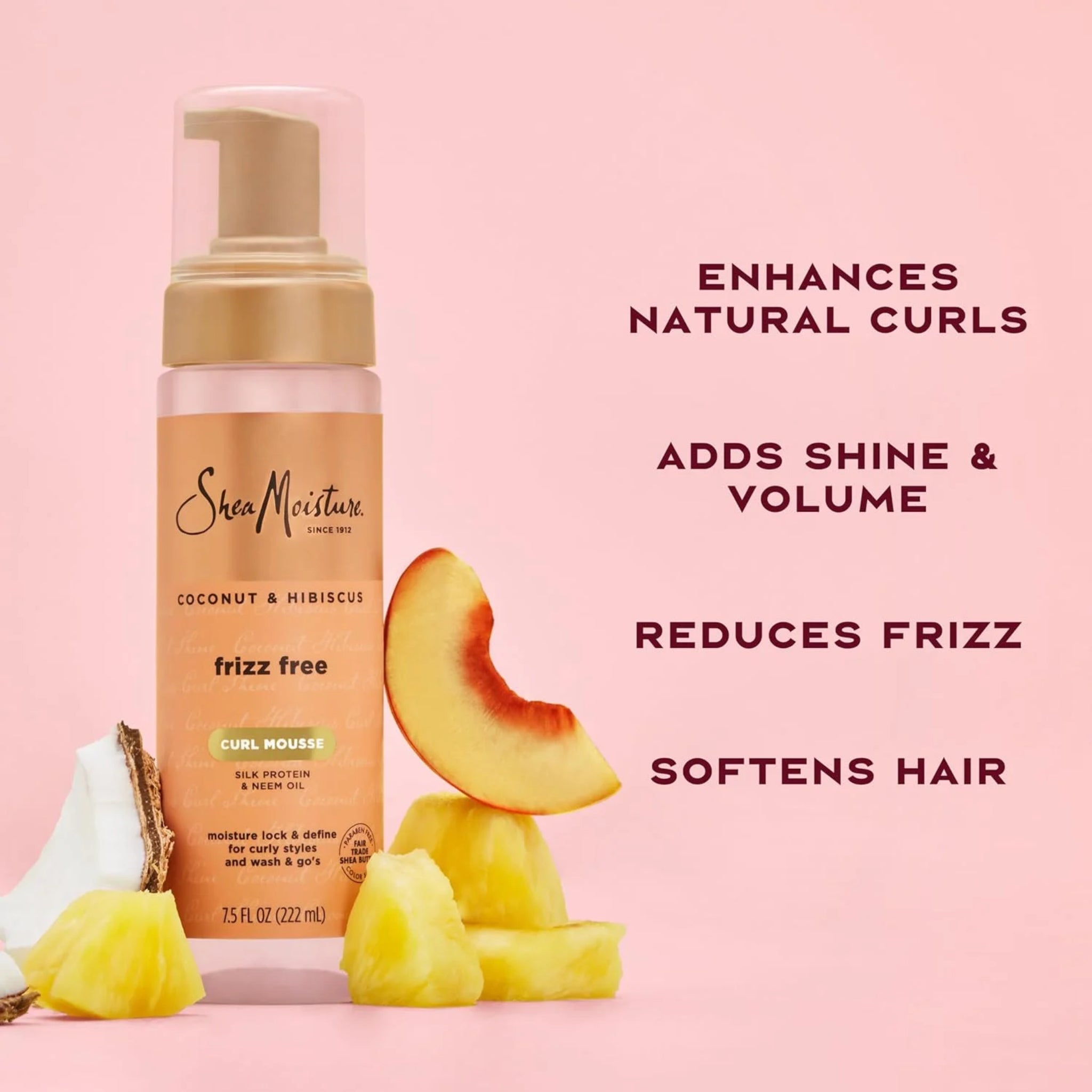 SheaMoisture Coconut & Hibiscus Frizz Free Curl Mousse flaske med kokos, ananas og ferskenskiver på lyserød baggrund.